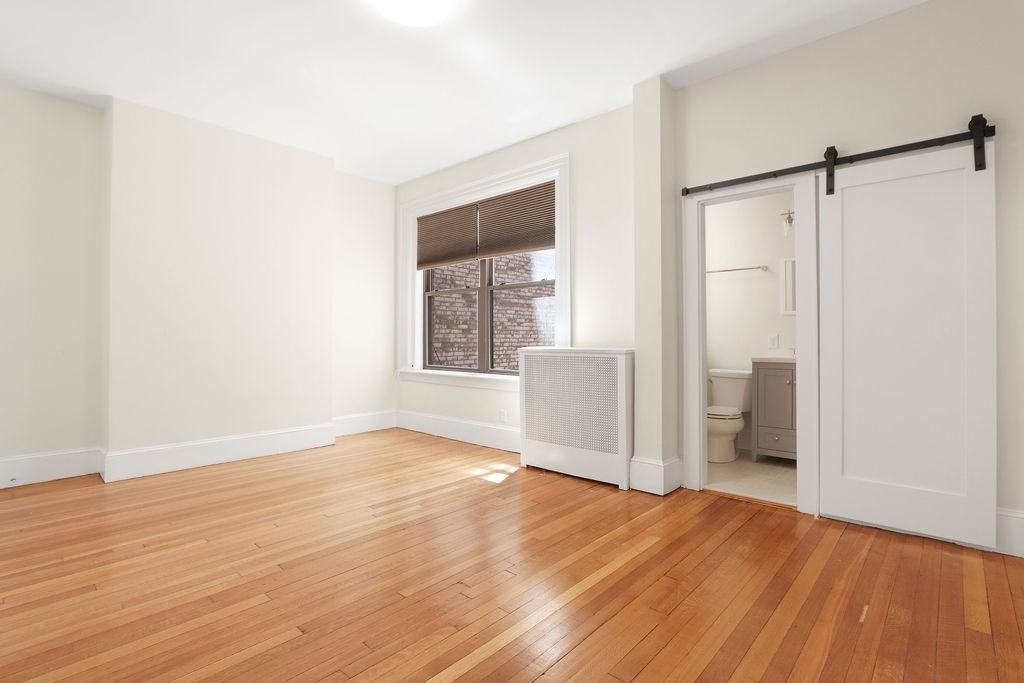 382 Commonwealth Avenue, Unit 24 Boston, MA 02215 - Photo 24 of 36 a view of an empty room with wooden floor and a window