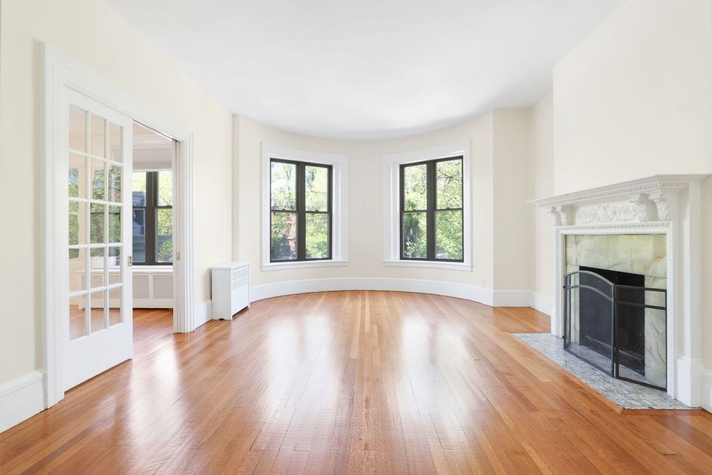 382 Commonwealth Avenue, Unit 24 Boston, MA 02215 - Photo 5 of 36 an empty room with fireplace wooden floor and windows