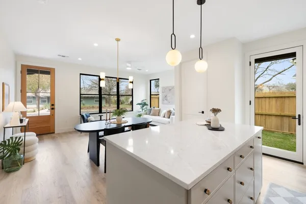 a kitchen with a sink a counter top space and living room view