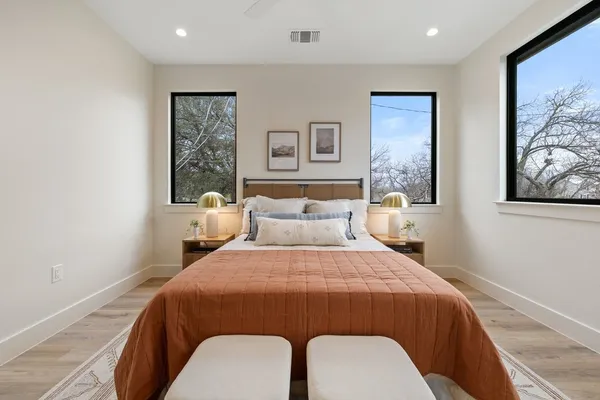 a bedroom with a bed two wall painting and a window