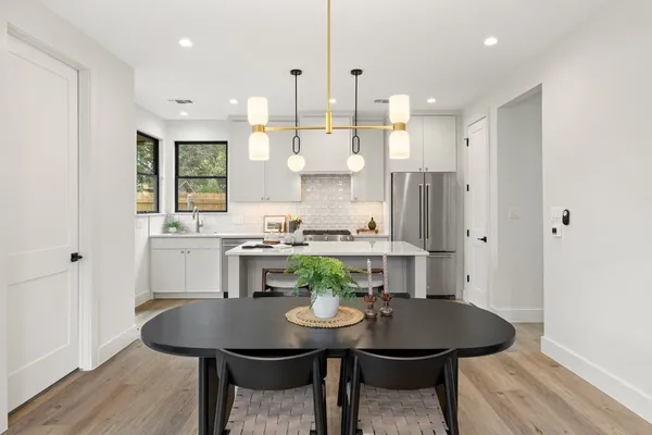 a kitchen with stainless steel appliances kitchen island a table and chairs in it