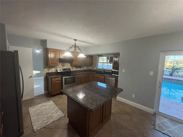 a kitchen with stainless steel appliances granite countertop a sink stove and refrigerator
