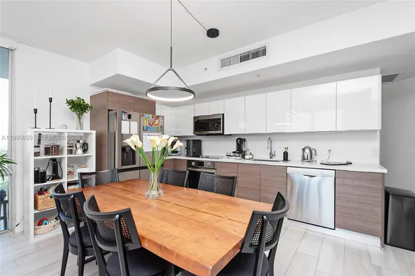 a kitchen with stainless steel appliances granite countertop a dining table chairs refrigerator and microwave