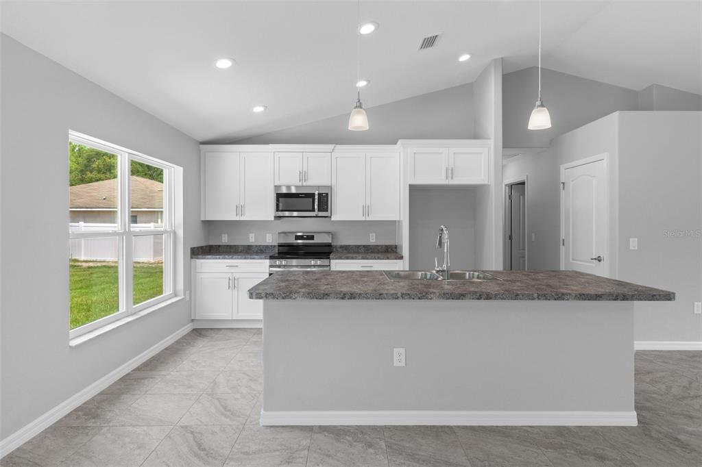 2492 Lackland Avenue Spring Hill, FL 34608 - Photo 9 of 30 a large kitchen with kitchen island a large counter top and stainless steel appliances