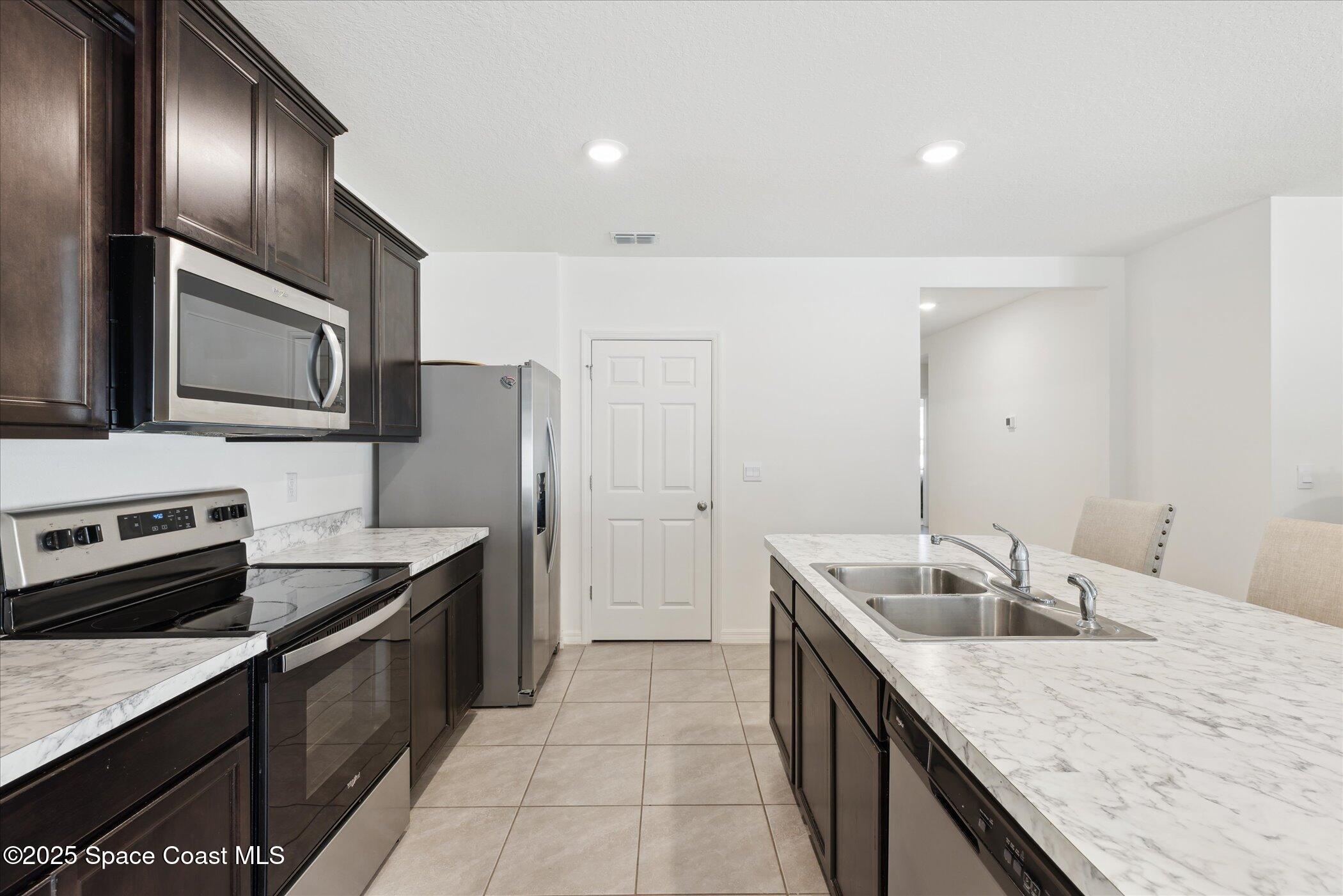 967 Trinity Street Rockledge, FL 32955 - Photo 14 of 40 a kitchen with stainless steel appliances granite countertop a sink stove and refrigerator