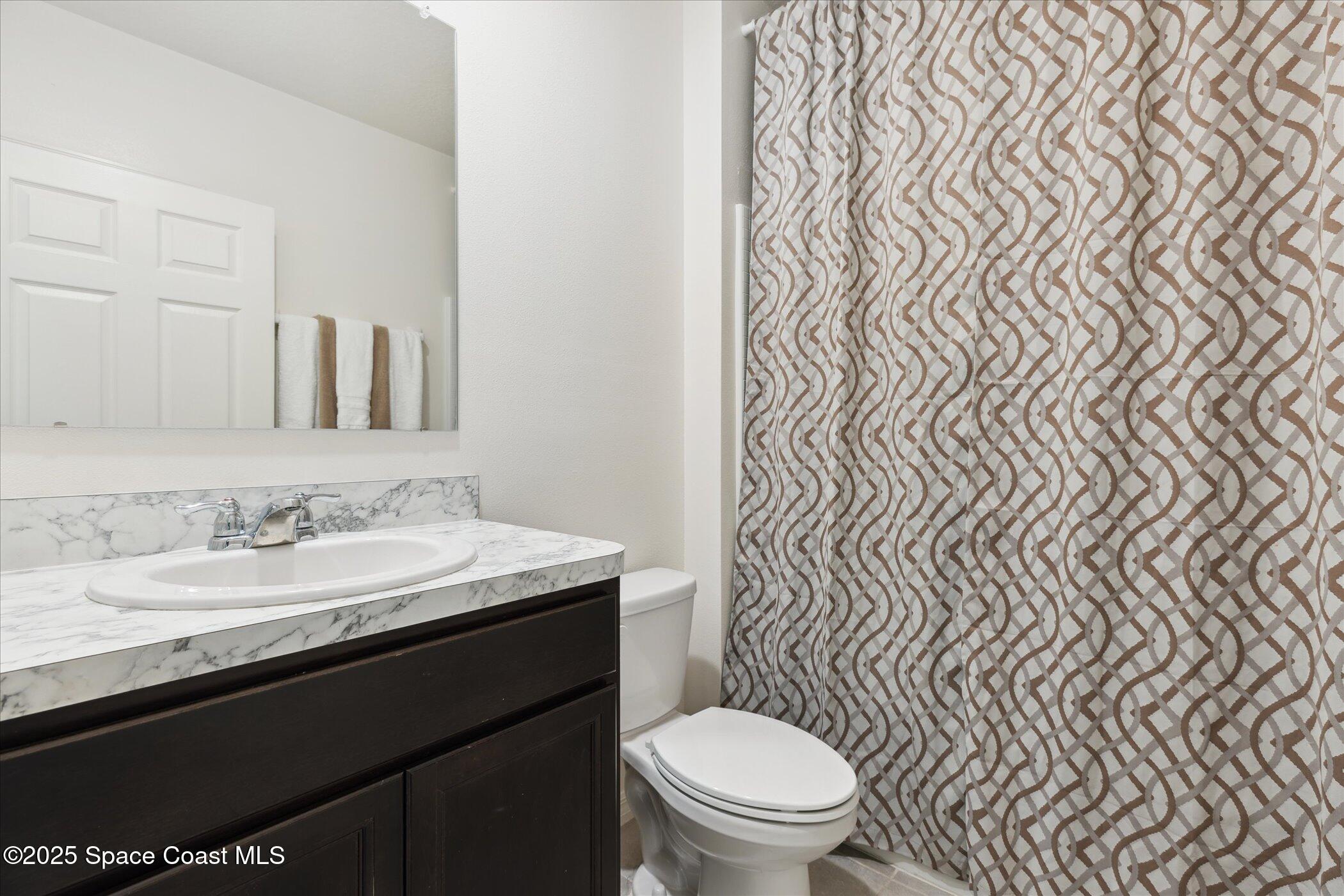 967 Trinity Street Rockledge, FL 32955 - Photo 28 of 40 a bathroom with a granite countertop toilet sink and mirror