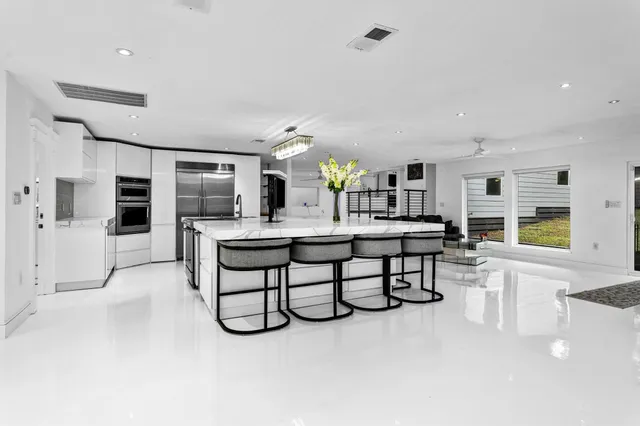 a large white kitchen with a large window and stainless steel appliances