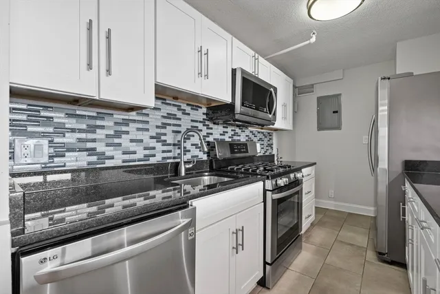 a kitchen with stainless steel appliances granite countertop a stove a microwave and a refrigerator