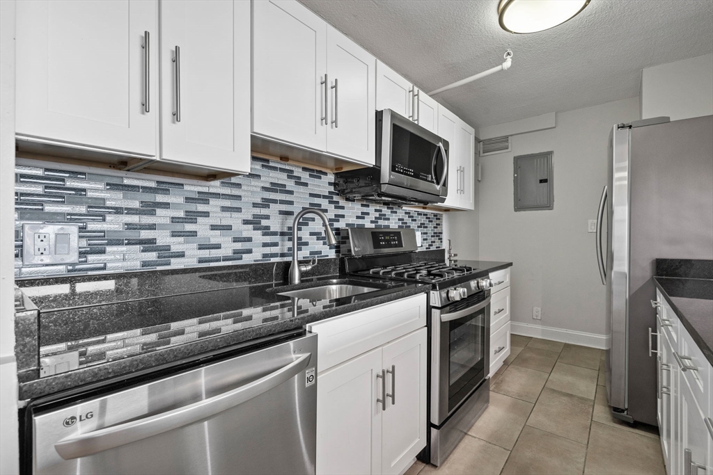 151 Tremont Street, Unit 24P Boston, MA 02111 - Photo 11 of 38 a kitchen with stainless steel appliances granite countertop a stove a microwave and a refrigerator