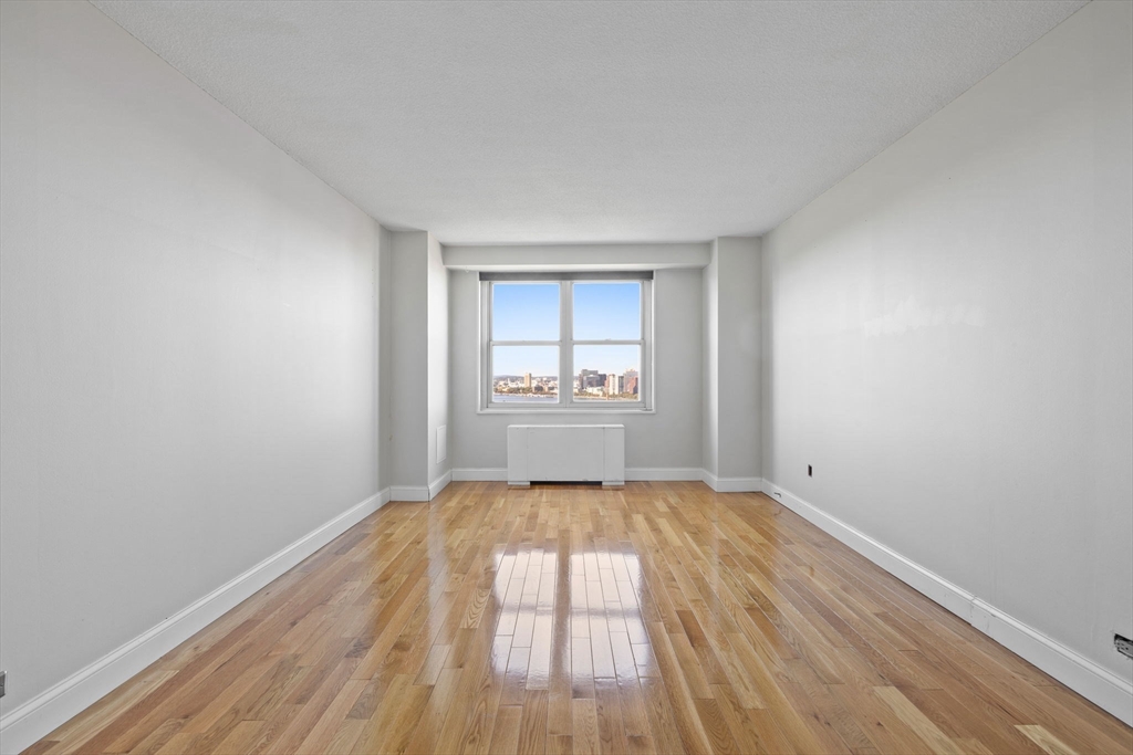 151 Tremont Street, Unit 24P Boston, MA 02111 - Photo 25 of 38 a view of an empty room with a window and wooden floor