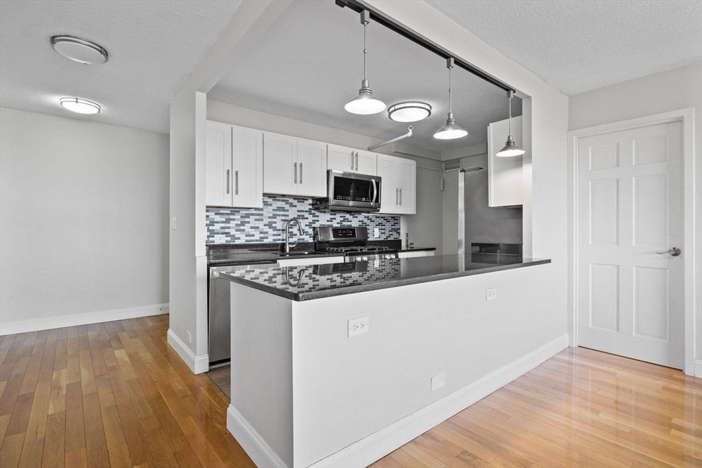 151 Tremont Street, Unit 24P Boston, MA 02111 - Photo 9 of 38 a kitchen with stainless steel appliances granite countertop a stove top oven a sink and a refrigerator