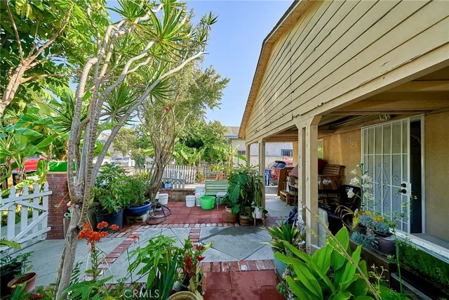 a view of a patio with table and chairs potted plants and large tree