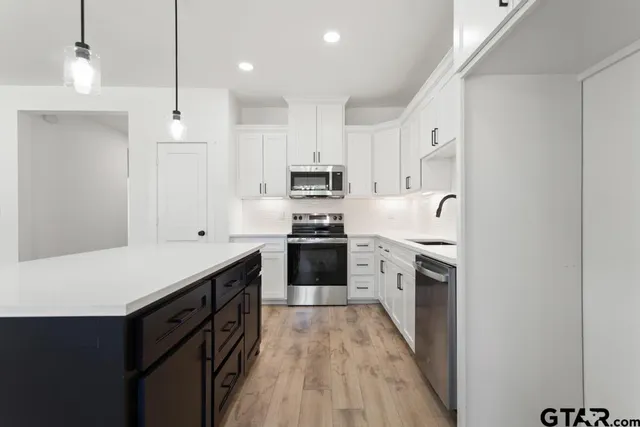 a kitchen with granite countertop white cabinets and stainless steel appliances