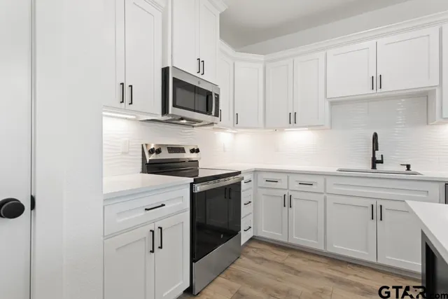 a kitchen with white cabinets and black appliances