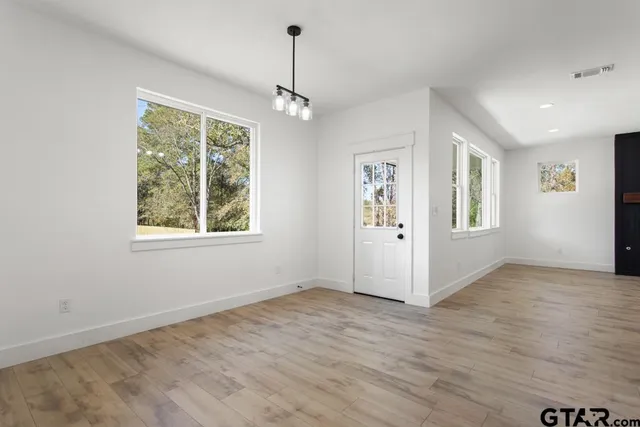 a view of an empty room with a window and wooden floor