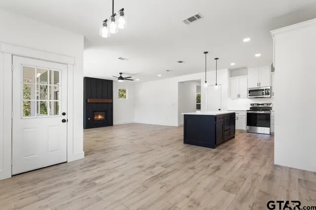 a large kitchen with stainless steel appliances kitchen island granite countertop a refrigerator a stove a sink dishwasher and a refrigerator with wooden floor