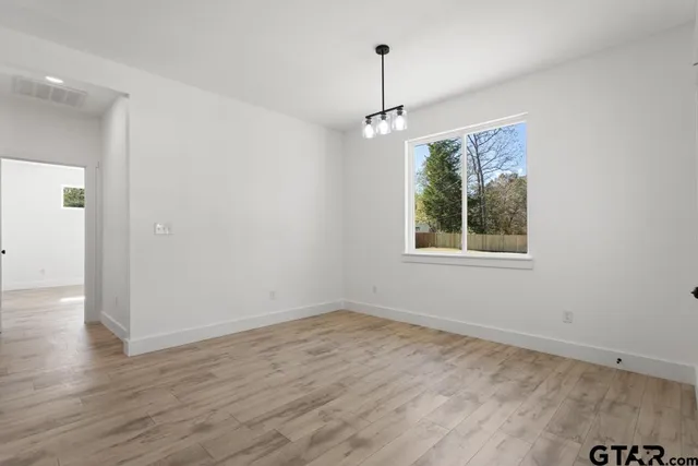 a view of an empty room with wooden floor ceiling fan and a window