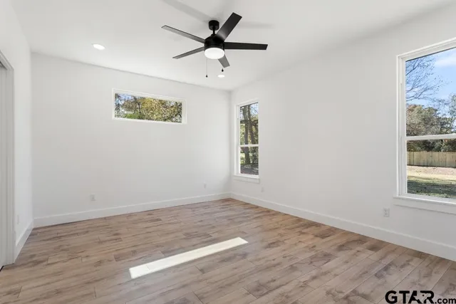 an empty room with wooden floor and windows