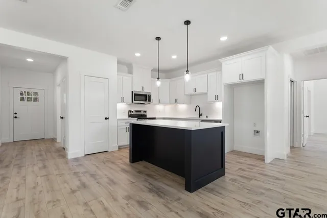 a large kitchen with stainless steel appliances kitchen island granite countertop a refrigerator and a sink