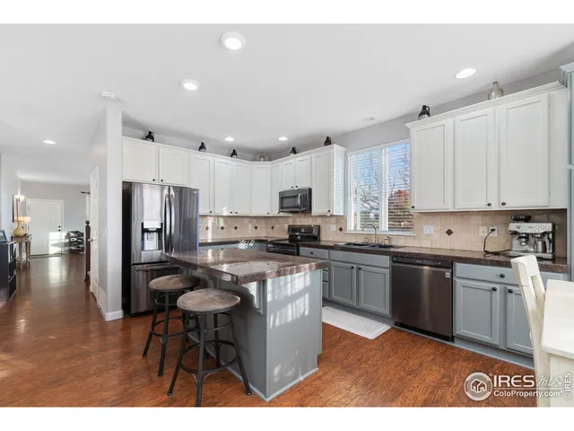 a kitchen with stainless steel appliances granite countertop a stove top oven a sink refrigerator and cabinets
