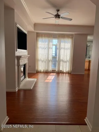 an empty room with wooden floor fireplace and windows