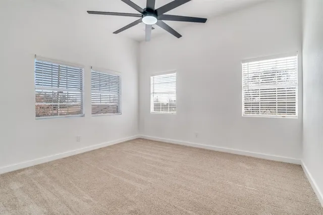 an empty room with windows and fan