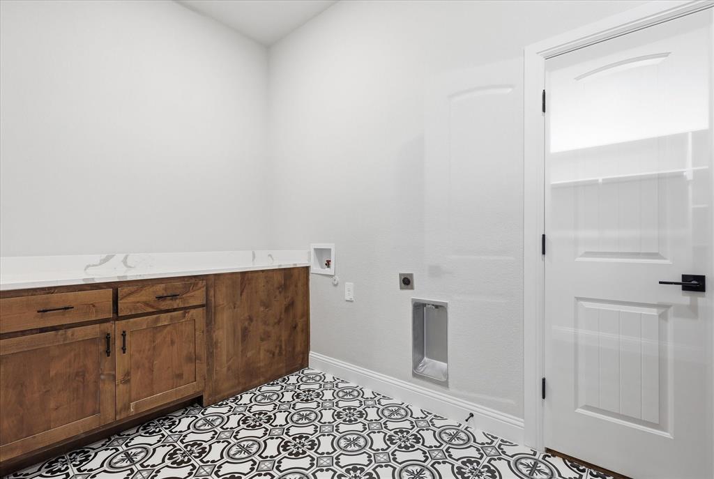 120 Grace Vw Road Weatherford, TX 76088 - Photo 20 of 40 Laundry area featuring patterned floor tile, wood-finish cabinetry, a white countertop, and a white paneled door with matte black hardware