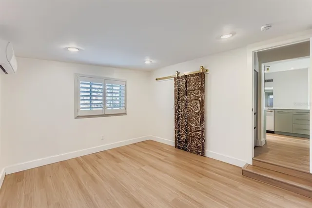 an empty room with wooden floor and a bathroom