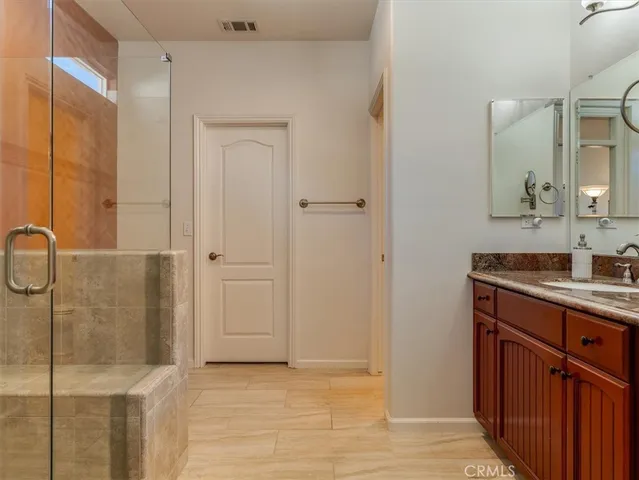 a bathroom with a granite countertop sink a mirror and a shower