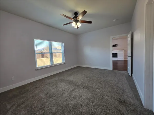 an empty room with ceiling fan and windows
