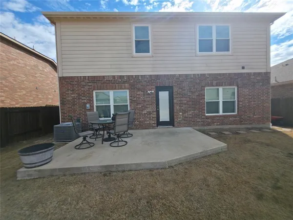 a view of a brick house with a patio and a yard