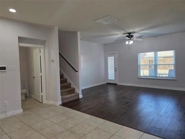 an empty room with wooden floor fan and windows