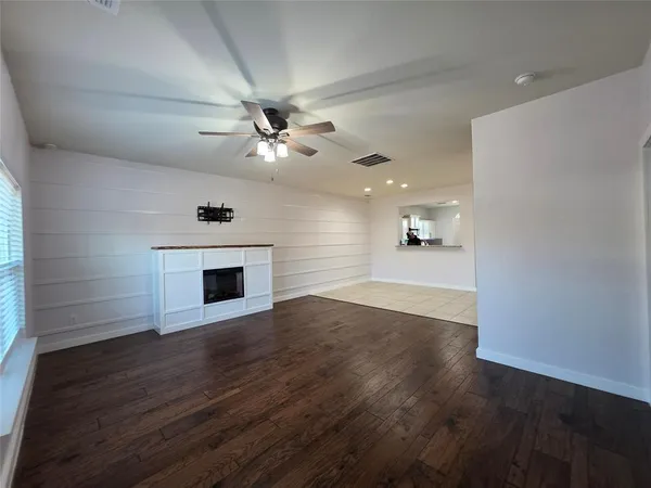 a view of an empty room with wooden floor and a fireplace