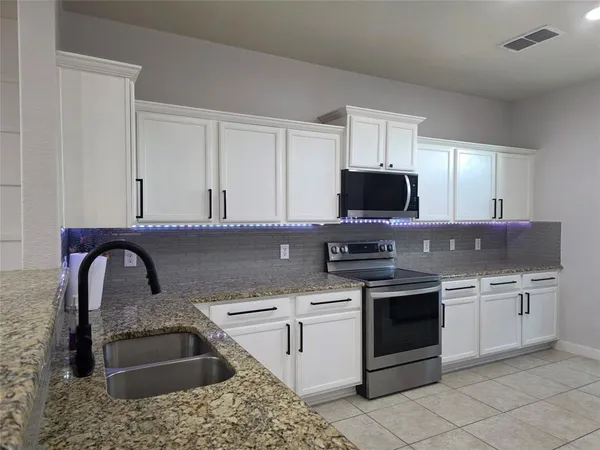 a kitchen with stainless steel appliances granite countertop a sink stove and microwave