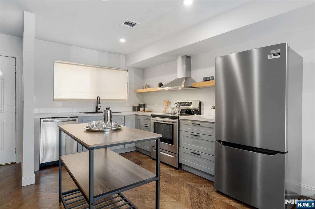 1110 River Road, Unit 102 Edgewater, NJ 07020 - Photo 6 of 18 a kitchen with a refrigerator a stove a sink and white cabinets with wooden floor