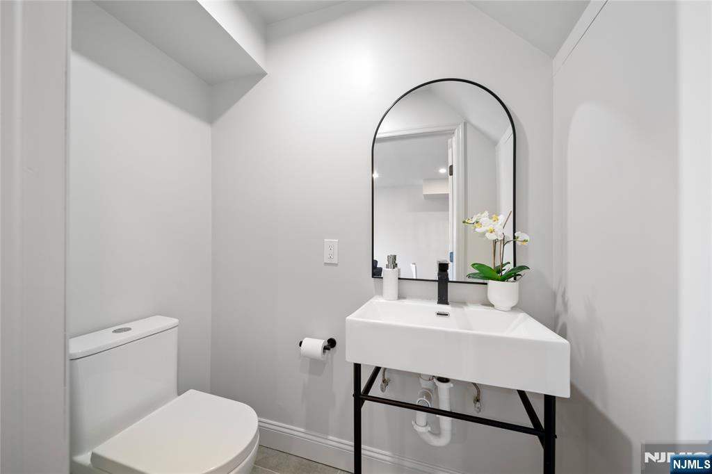 1110 River Road, Unit 102 Edgewater, NJ 07020 - Photo 7 of 18 a bathroom with a sink a toilet and mirror