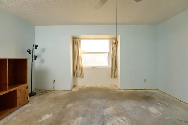 a view of a big room with window and chandelier fan
