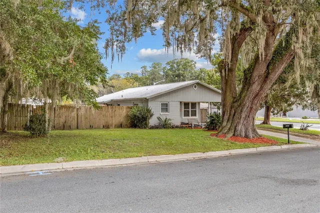 a view of a house with a yard and large trees