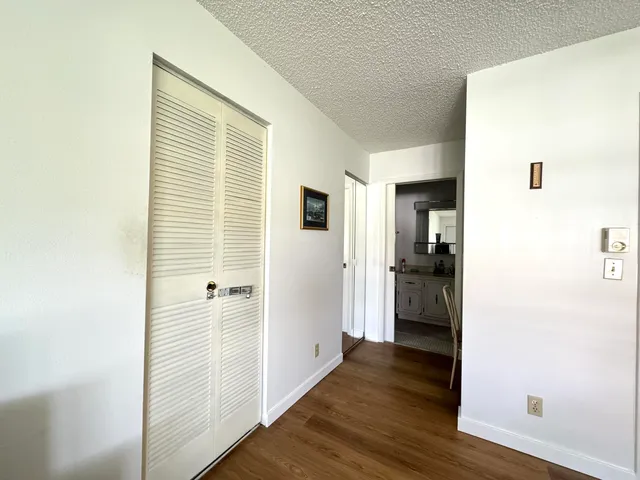 a view of a hallway with wooden floor and a bathroom