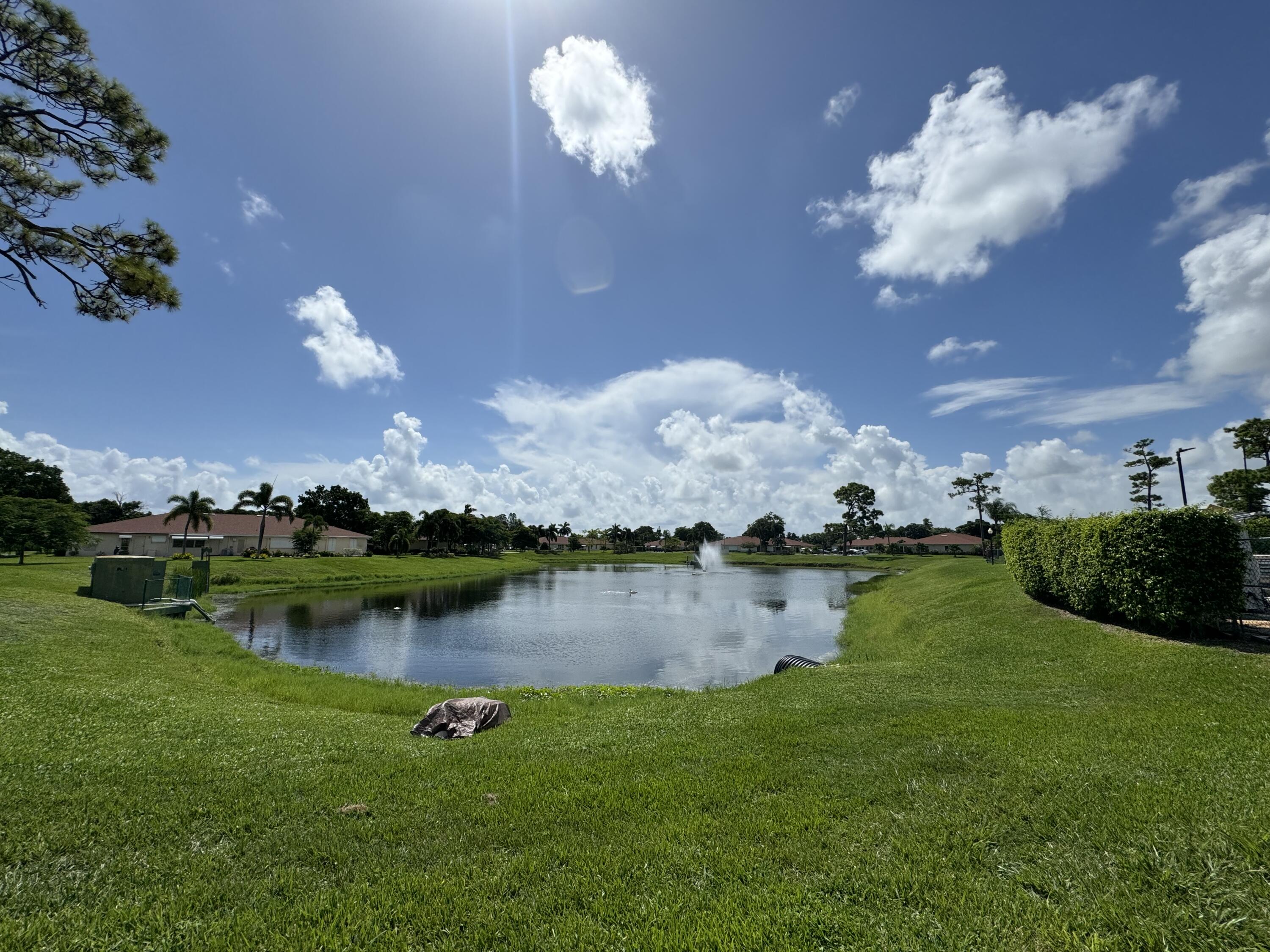4675 Northwest 3rd Court, Unit B Delray Beach, FL 33445 - Photo 20 of 28 a view of a lake with lawn chairs and a large tree
