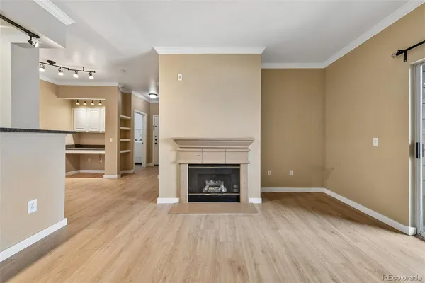 an empty room with wooden floor fireplace and windows