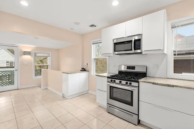 a kitchen with granite countertop a stove top oven and cabinets
