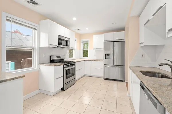 a kitchen with white cabinets and stainless steel appliances