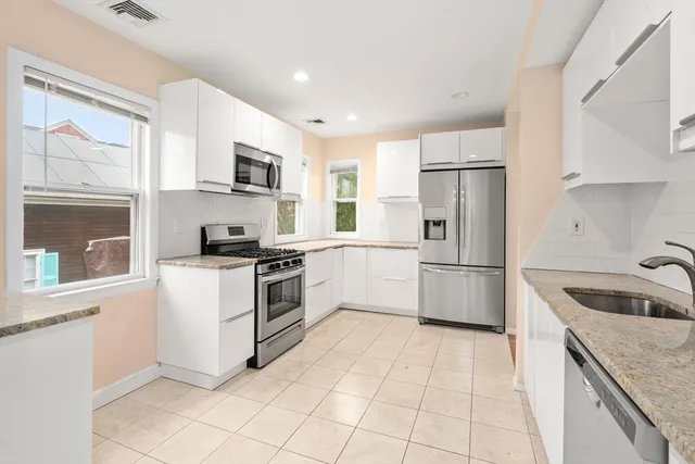a kitchen with white cabinets and stainless steel appliances