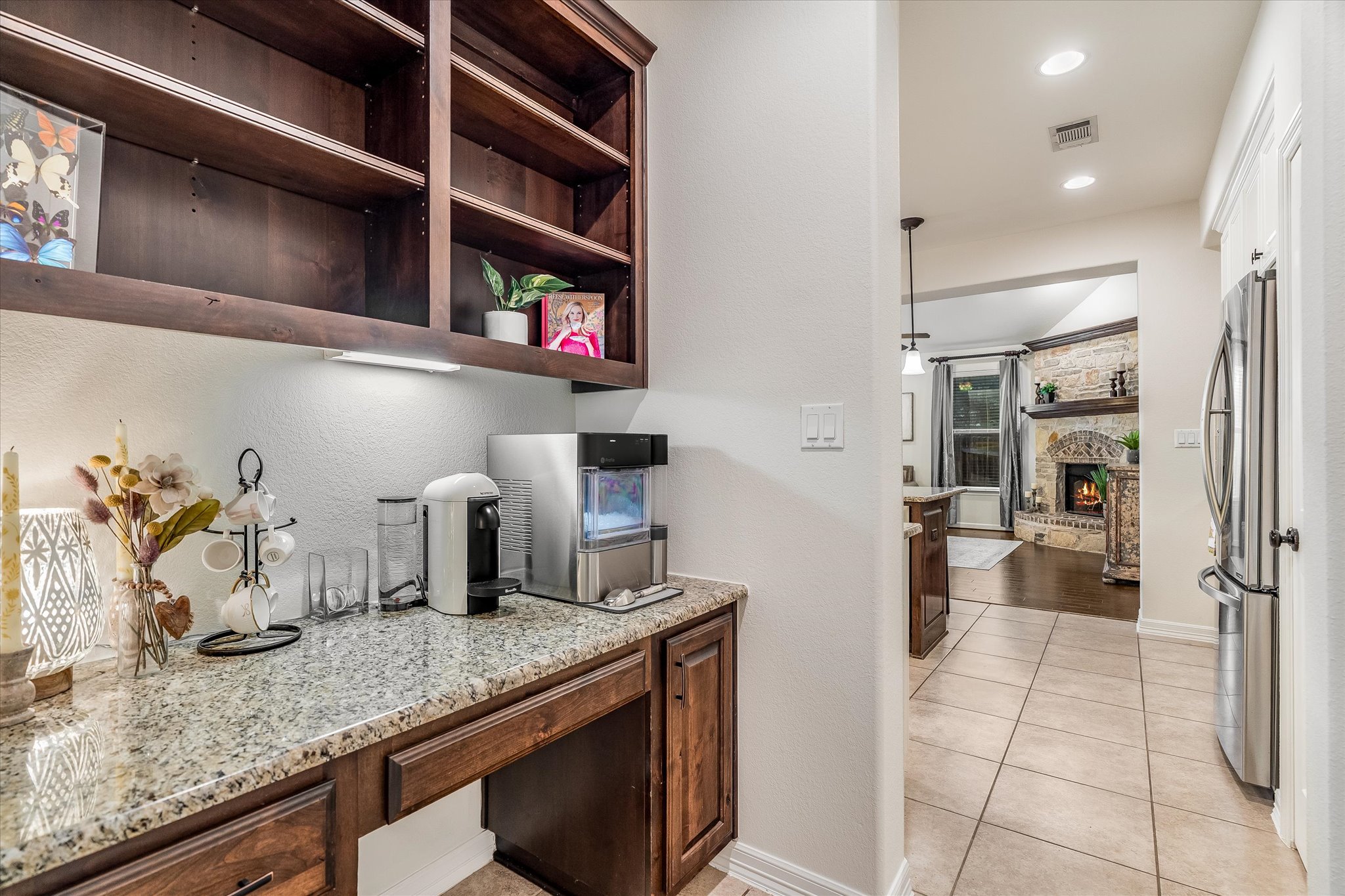 226 Galloway Lane Austin, TX 78737 - Photo 13 of 30 Kitchen featuring a stone fireplace, freestanding refrigerator, light stone counters, light tile patterned floors, and recessed lighting