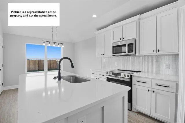 a view of a kitchen with kitchen island a sink stainless steel appliances and cabinets