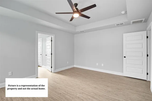 a view of a room with wooden floor and a ceiling fan