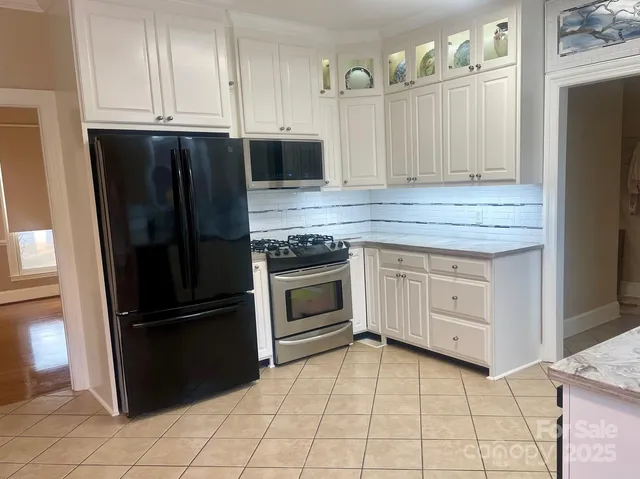 a kitchen with granite countertop a refrigerator stove and cabinets