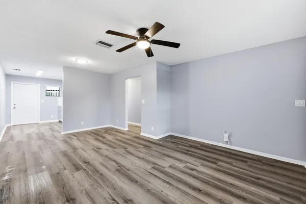a view of empty room with wooden floor and ceiling fan