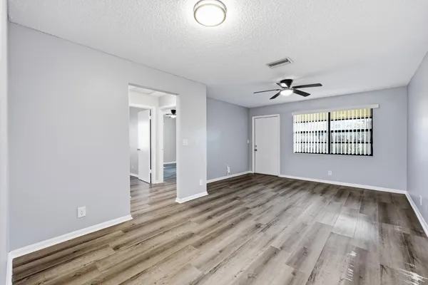 an empty room with wooden floor and windows